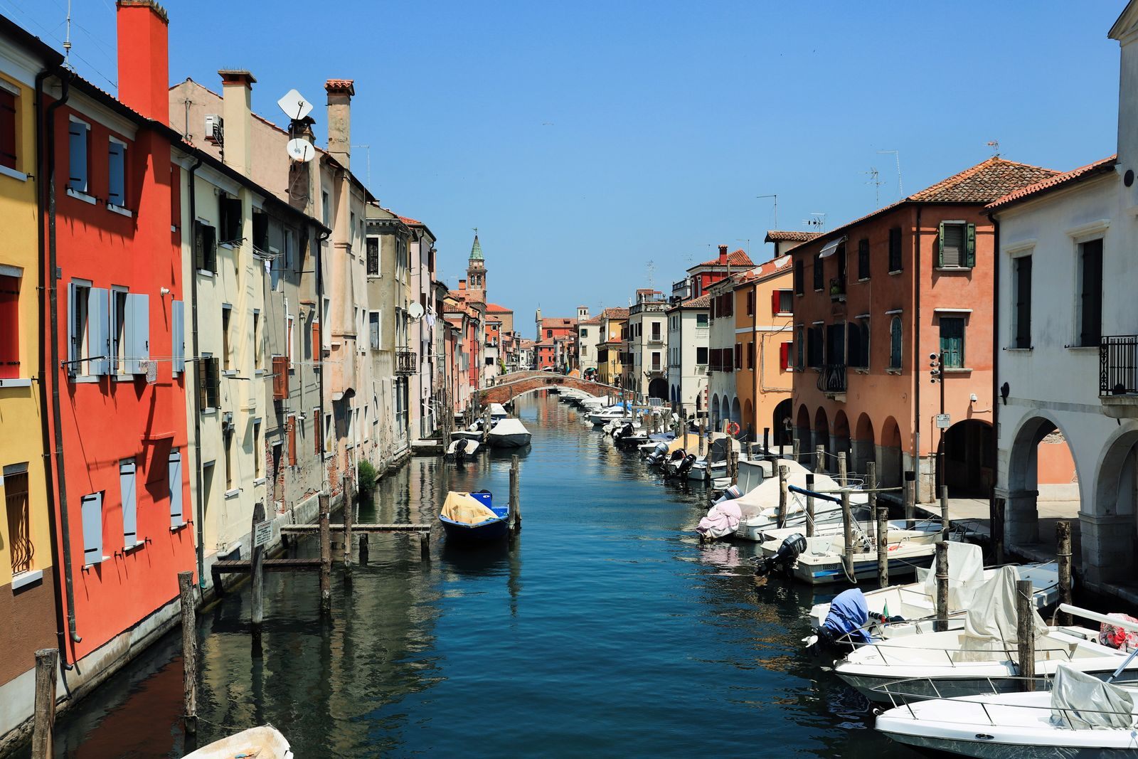 Boats lining a canal between colourful houses in Chioggia on the Venetian lagoon